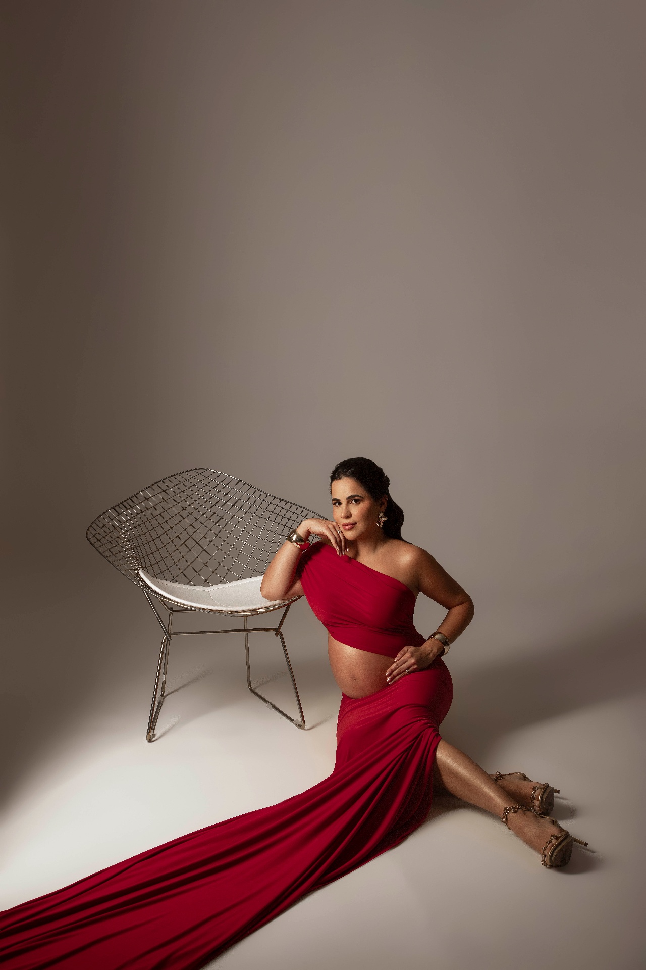 Gestante com vestido vermelho longo em ensaio elegante